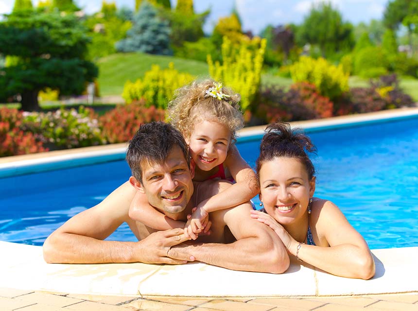 Father, daughter, and wife in pool smiling